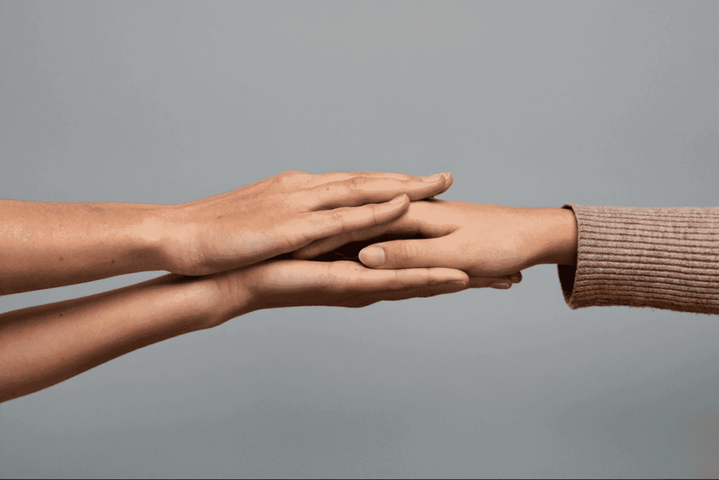 На фото зображені долоні, які тримають руку іншої людини.