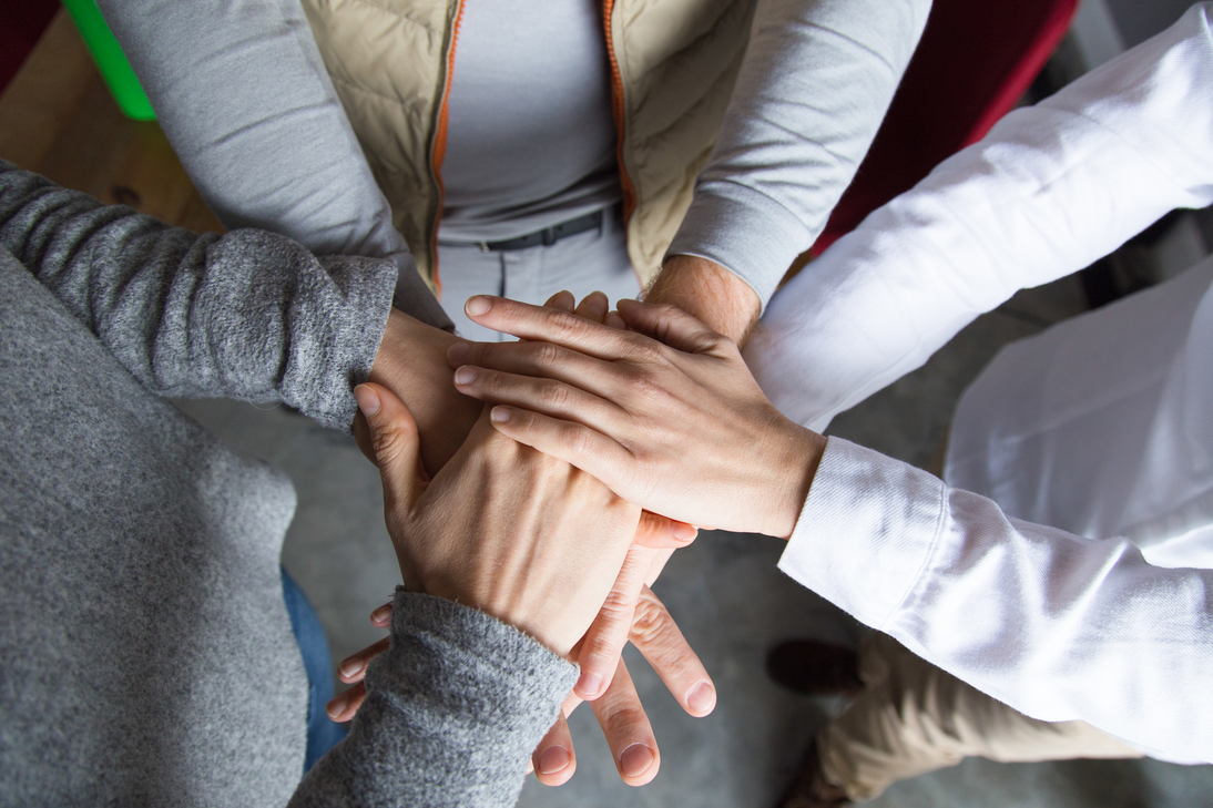 На фото зображені руки людей, які лежать одна на одній